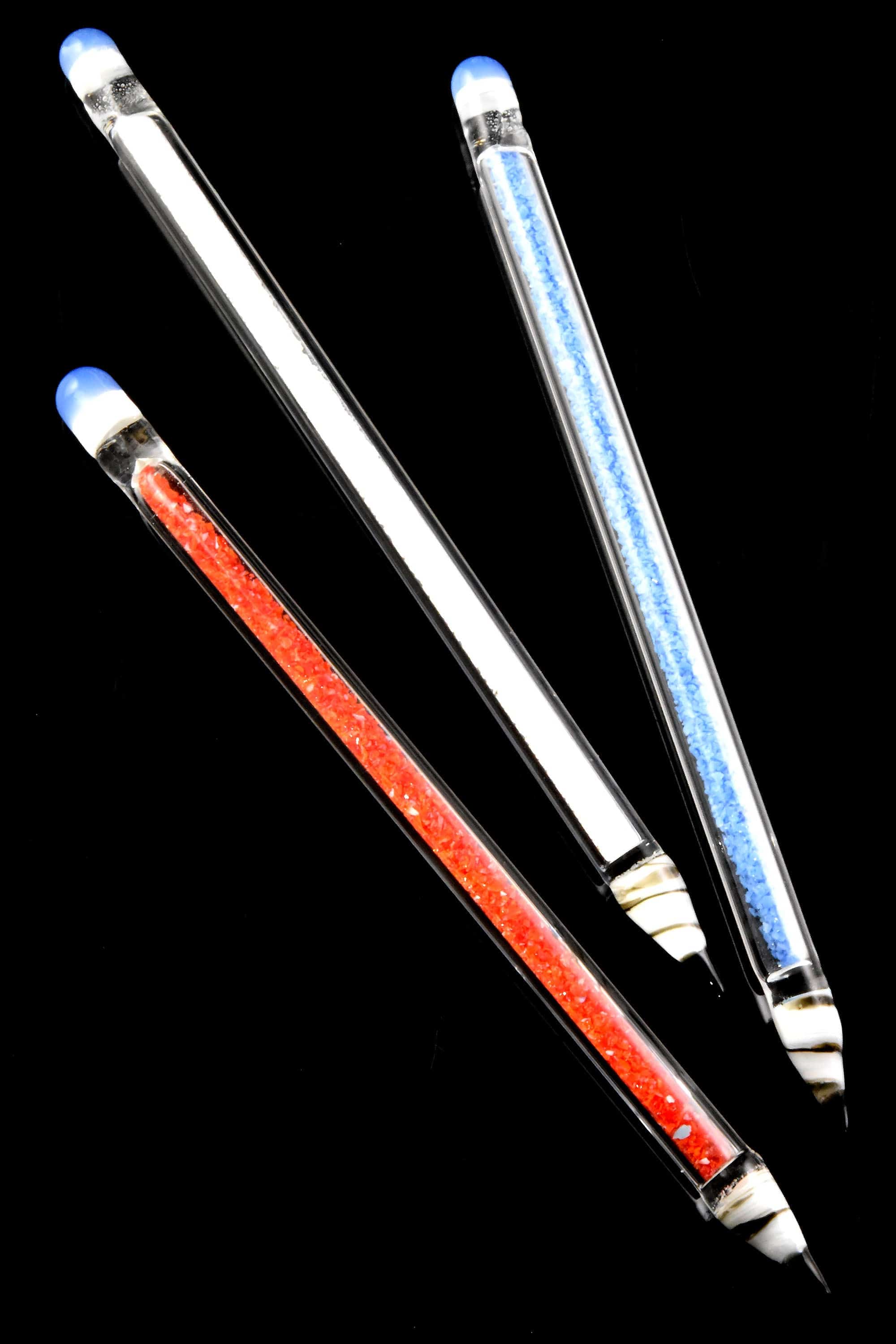 Angled close-up of three 6″ Primate Glass Pencil Dab Tool – 6″ glass tips with blue-capped ends and red and blue inner cores against a black background