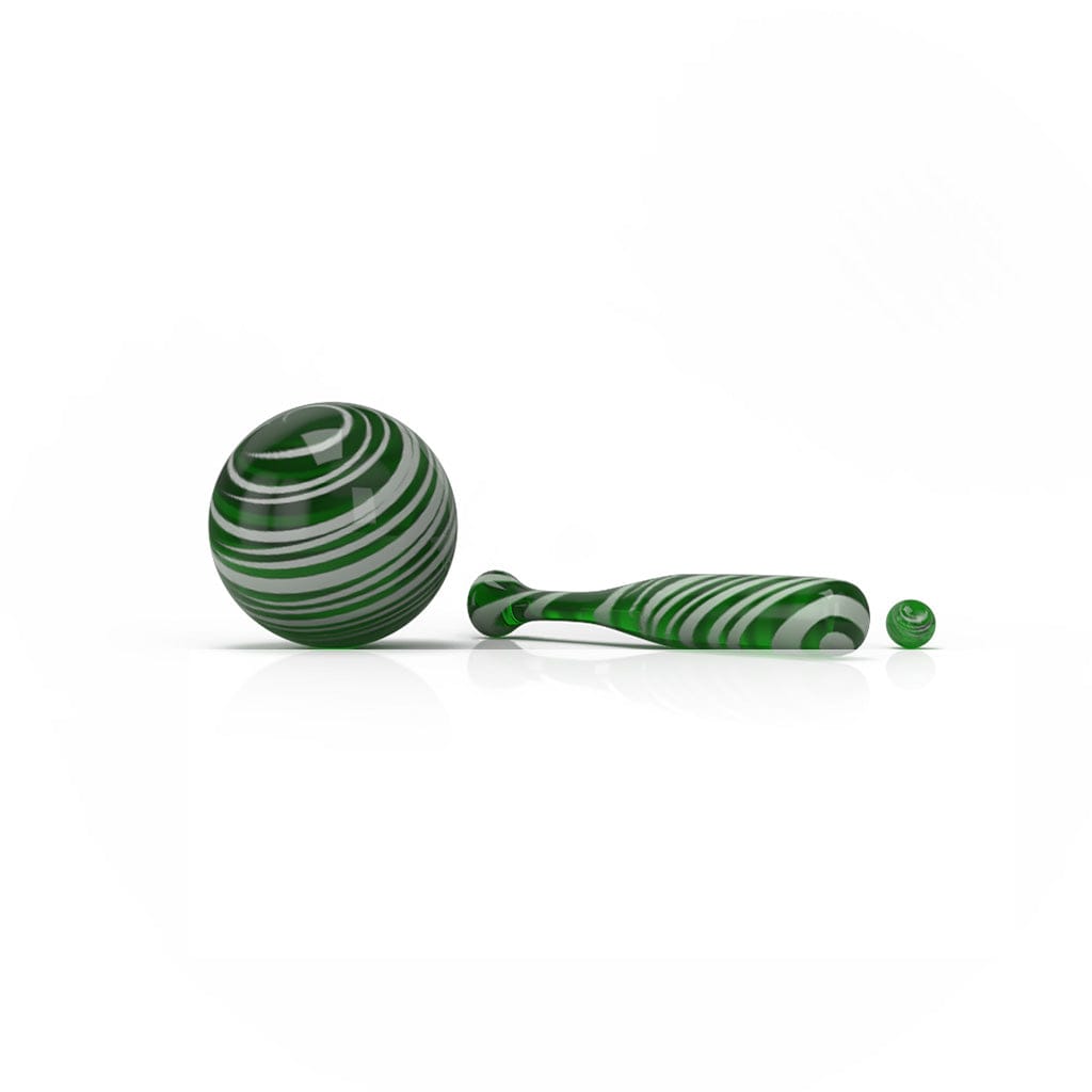 Low-angle view of the green, striped Honeybee Herb Dab Baseball Set showing a large glass ball, a matching elongated bat piece, and a small marble on a white reflective surface
