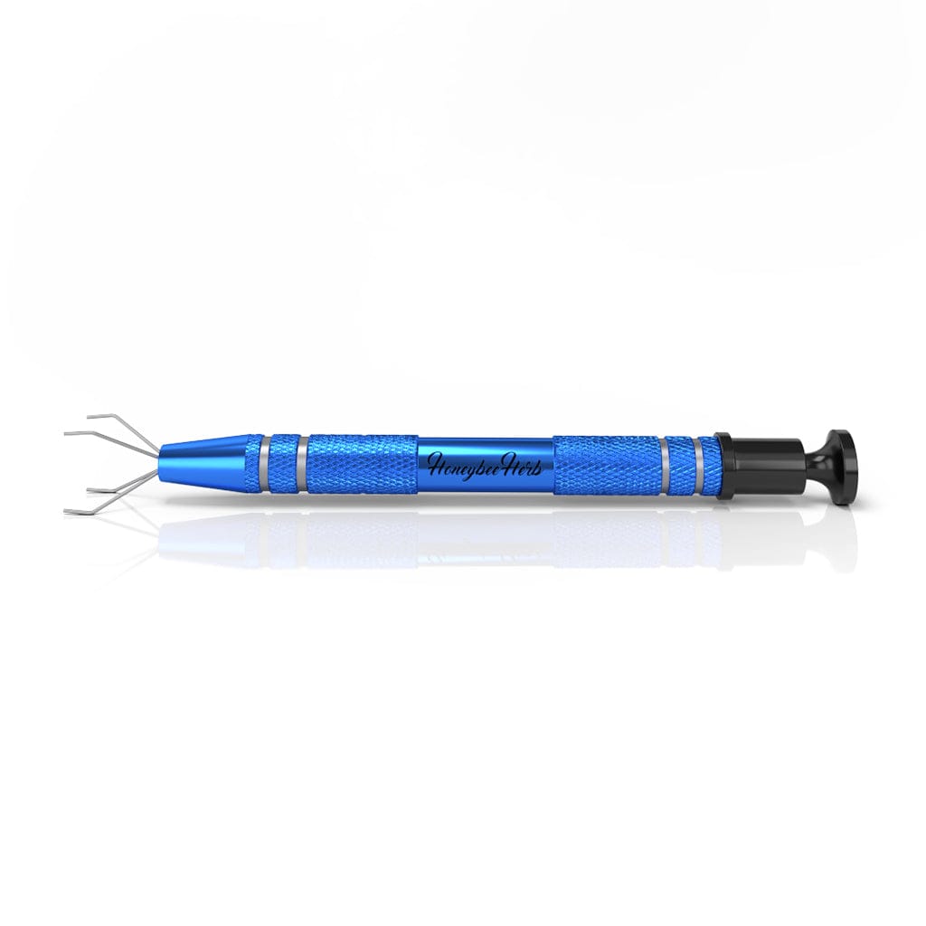 Side view of a metallic blue Honeybee Herb Dab Claw laid flat on a white reflective surface, showing its textured grip, four-pronged tip, and black plunger end.