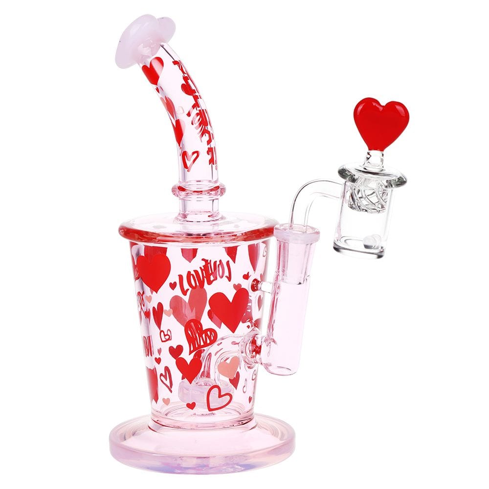 Angled front view of the Pulsar Valentine'S Love Hearts Glass Dab Rig Set - 8.5" / 14Mm F showing a pink glass rig covered in red hearts with a heart-topped banger against a white background