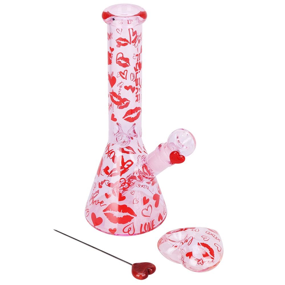 Angled front view of the Pulsar Valentine'S Xoxo Glass Beaker Water Pipe & Hand Pipe Set - 10" / 14Mm F, pink glass with red lips and hearts on a white background