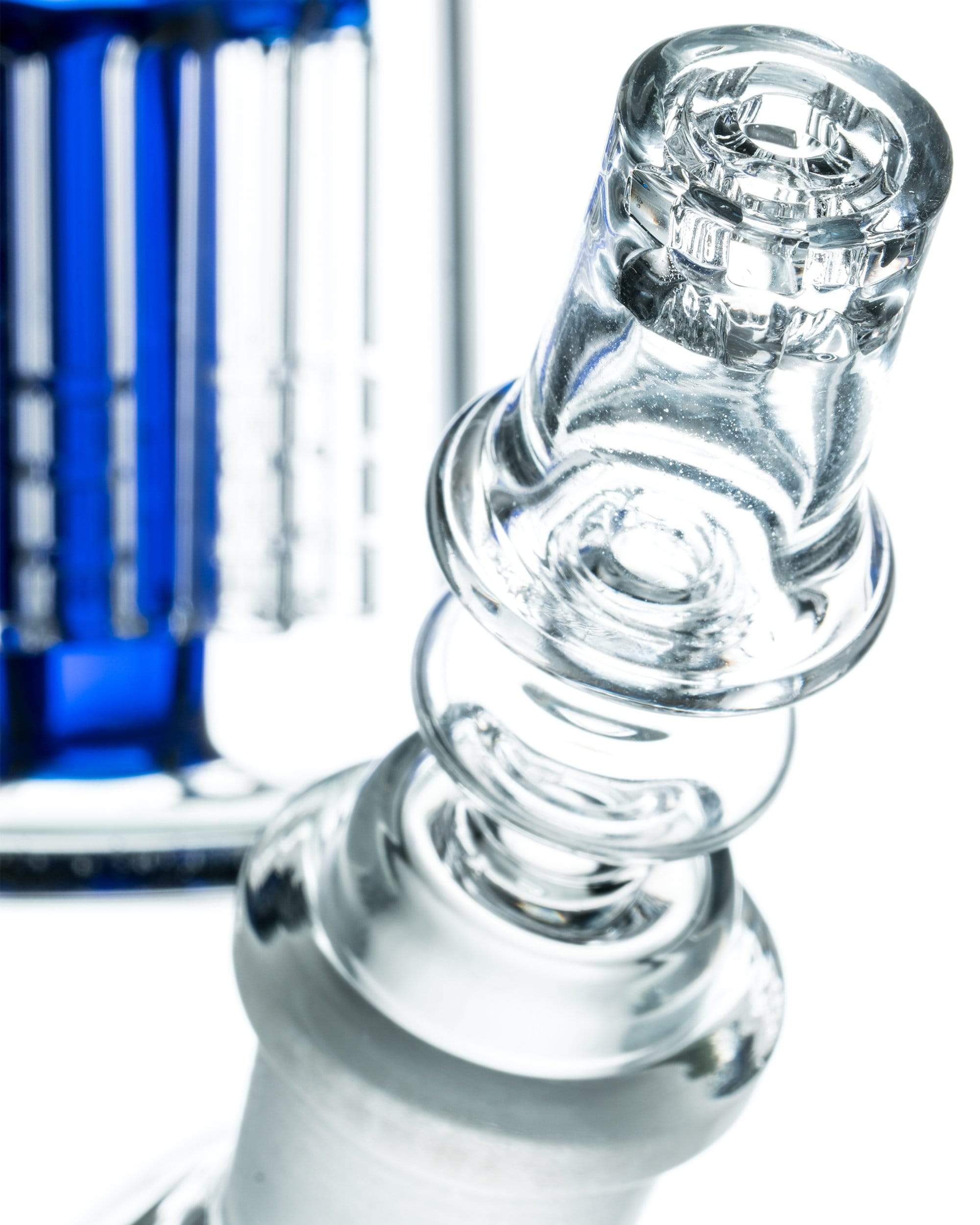 Close-up angled shot of the clear glass Diamond Knot Domeless Nail showing its spiral knot detail against a blurred blue background