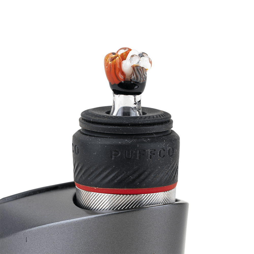 A close-up, angled view of the Coral PuffCo Peak Pro Glass Ball Cap, showing its smooth, rounded form and reflective surface.