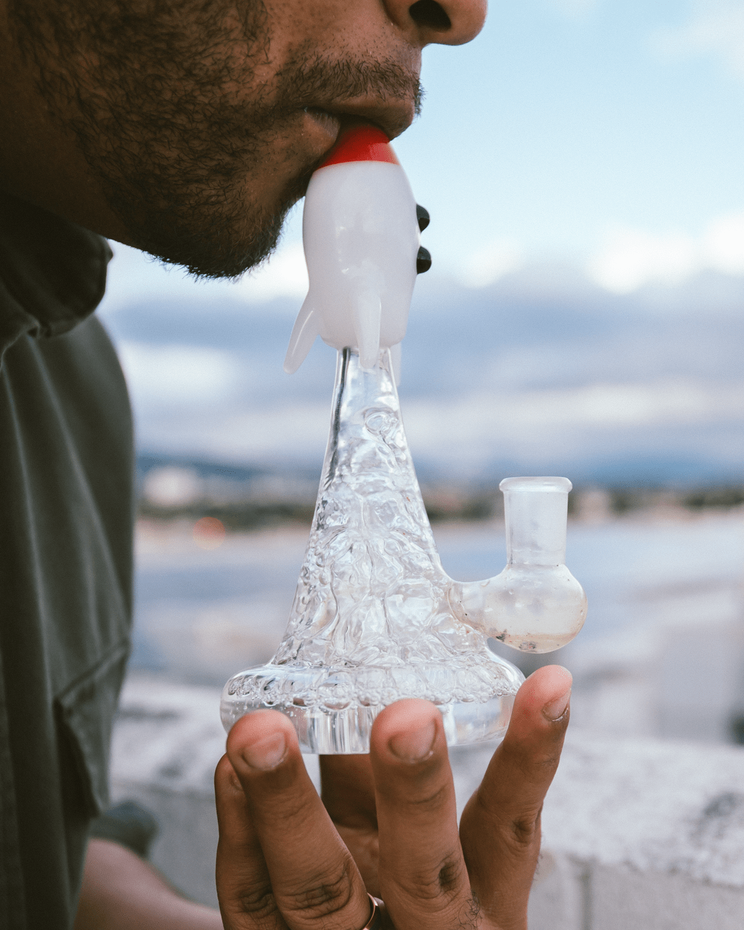 A close-up, front view of the Blastoff Rocket Bong, showcasing its clear glass construction and rocket-shaped design against a blurred background.
