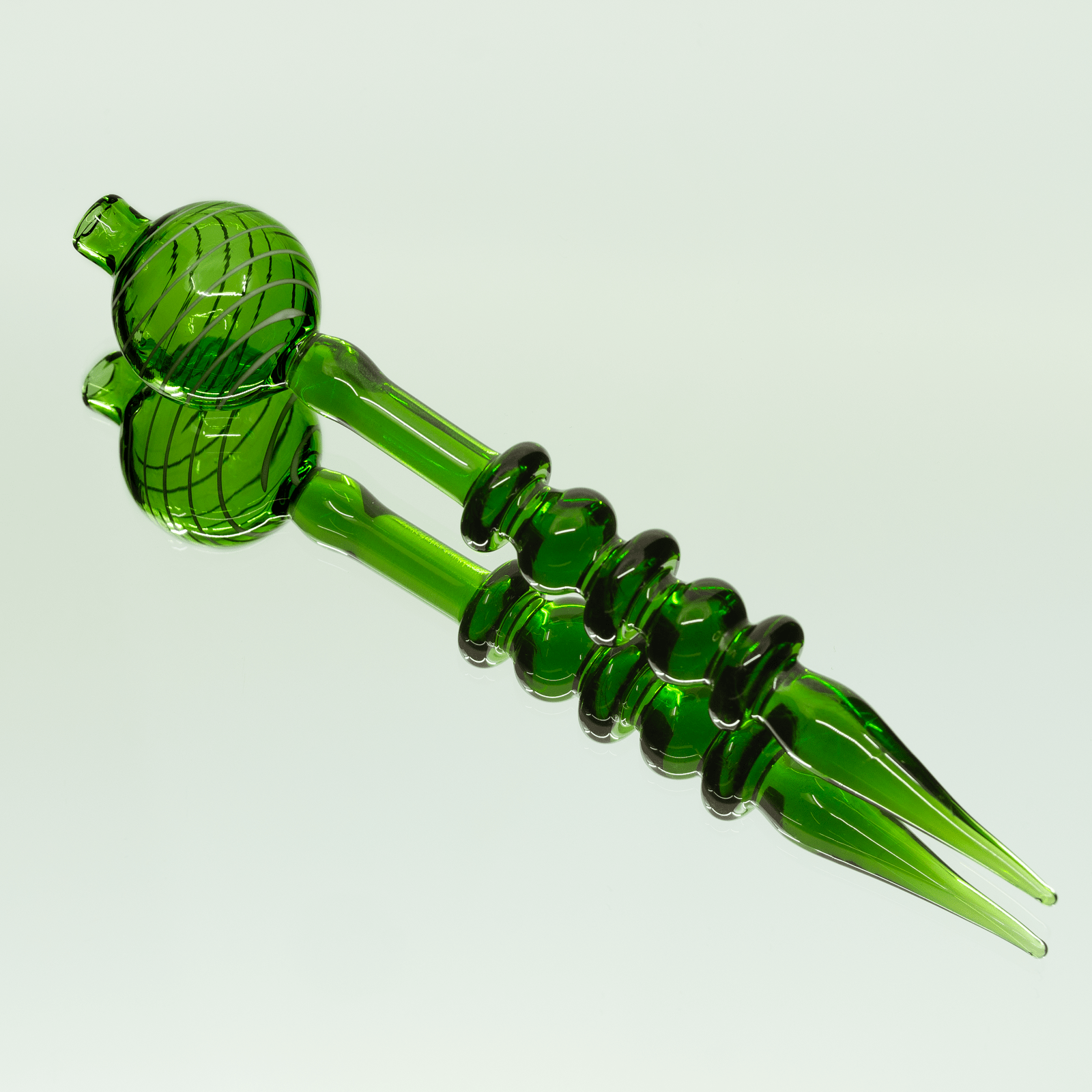 A close-up, angled view of the Bubble Head Dab Tool & Carb Cap, showcasing its smooth, green glass construction.