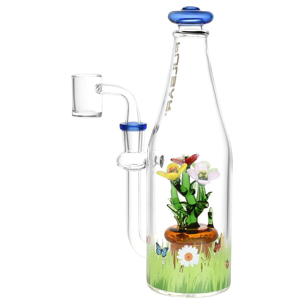 Right-side view of the Pulsar Flower Garden Bottle Rig showing a clear bottle with internal glass flowers, grassy decal and blue rim accents