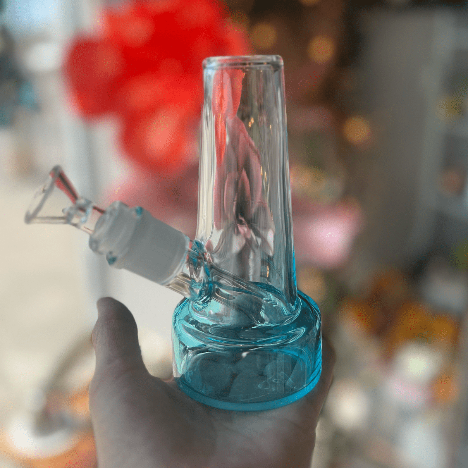 A close-up, angled view of the Ombré Bubbler, featuring a clear glass piece held against a blurred, colorful backdrop.