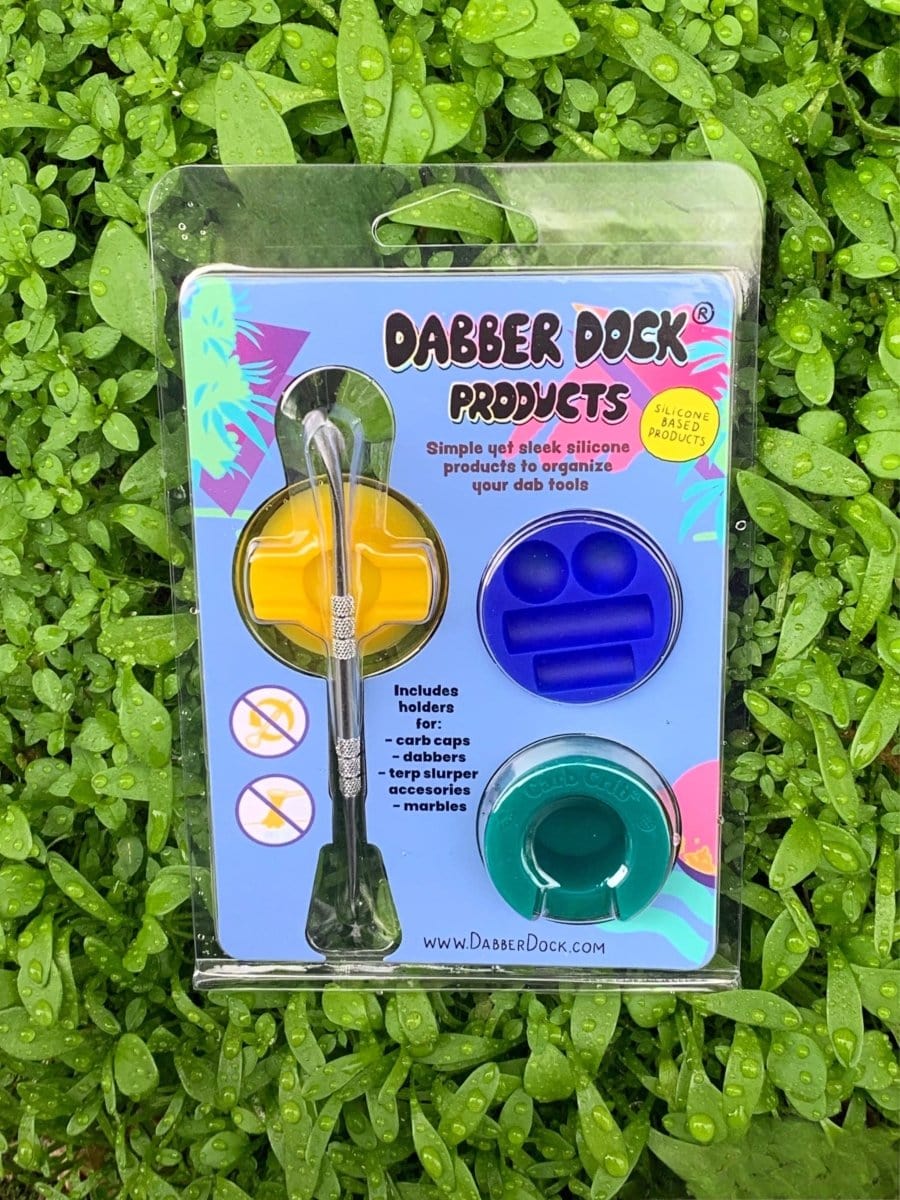 A slightly angled overhead shot displays the New Drop 3-pack, including a dabber, resting on a textured surface with branding visible.
