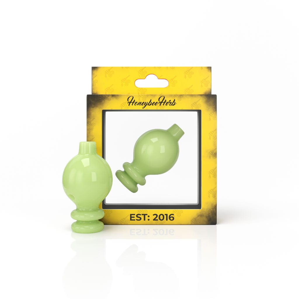Front three-quarter view of a blue MILK BUBBLE CARB CAP resting beside its yellow HoneybeeHerb windowed box on a white reflective surface.