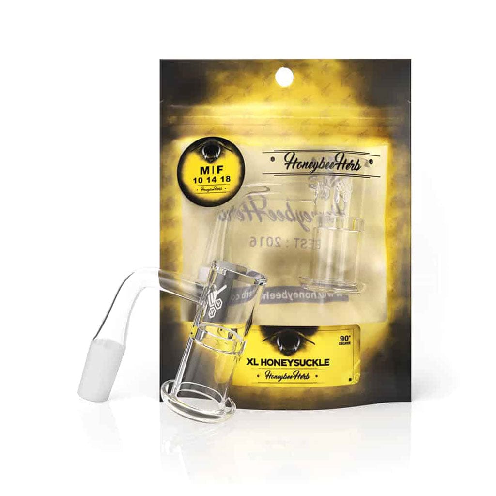 Front-three-quarter view of the Honeysuckle Xl Quartz Banger - 90Â° Degree | Yl glass banger resting against its yellow and black branded packaging, lit from above.
