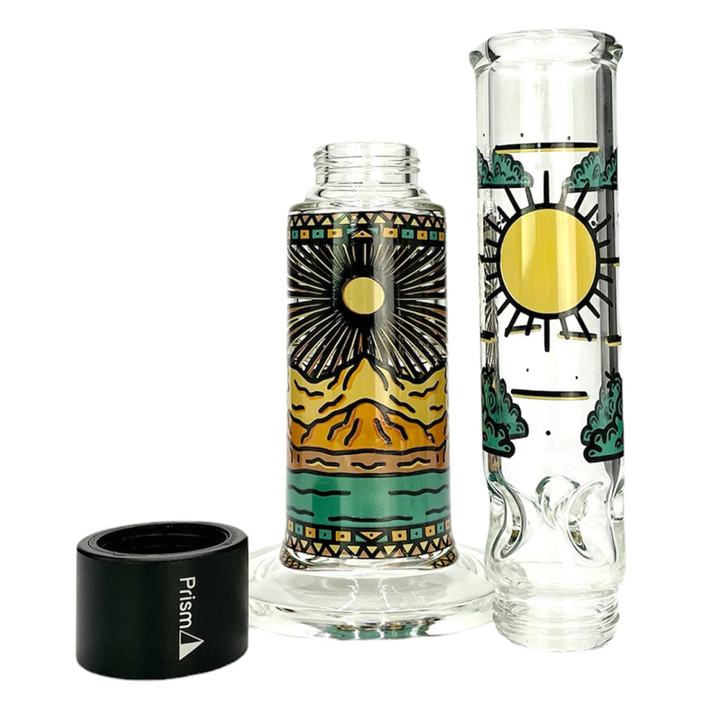 Angled front view of the Prism Desert Dream'N Big Honeycomb Single Stack showing two decorated clear glass cylinders with yellow sun and teal landscape motifs and a black Prism-branded base.