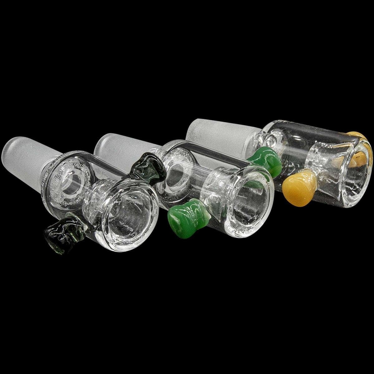Angled close-up of three Honeycomb Cylinder Bowl with Handles pieces in clear glass with small green and yellow handle knobs against a black background